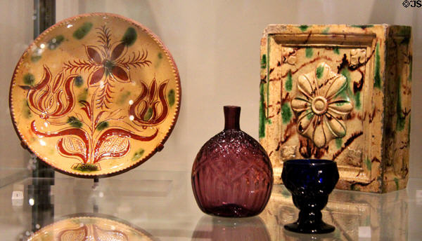 Earthenware pie plate (1828) from PA & stove tile (c1785) from NC plus glass bottle (c1770) & salt (1729-85) by Henry William Stiegel of Manheim, PA at Yale University Art Gallery. New Haven, CT.