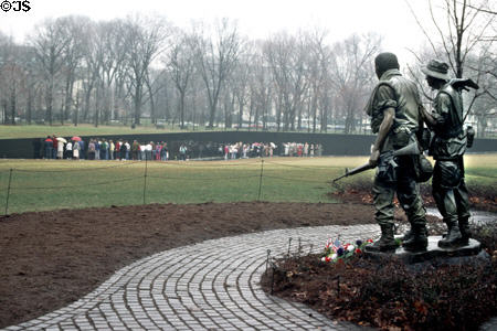Bronze soldiers carrying weapons look over Vietnam Memorial. Washington, DC.