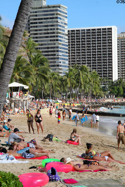 Sitting on sand on beach in Waikiki. Waikiki, HI.