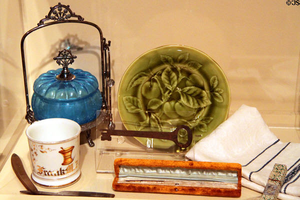 Blue glass condiment container (c1875), green Majolica plate (late 19thC), & shaving mug & razor at Sedgwick County Historical Museum. Wichita, KS.
