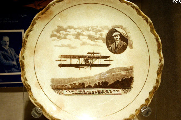 Souvenir plate of Glenn Curtiss & his aeroplane over Hammondsport, NY (c1920) by Carnation/McNicol of East Liverpool, OH at Henry Ford Museum. Dearborn, MI.