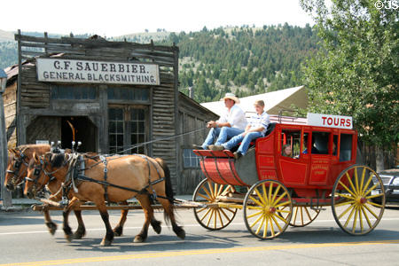 Tourist stagecoach passes before Sauerbier Blacksmith Shop (1863). Virginia City, MT.