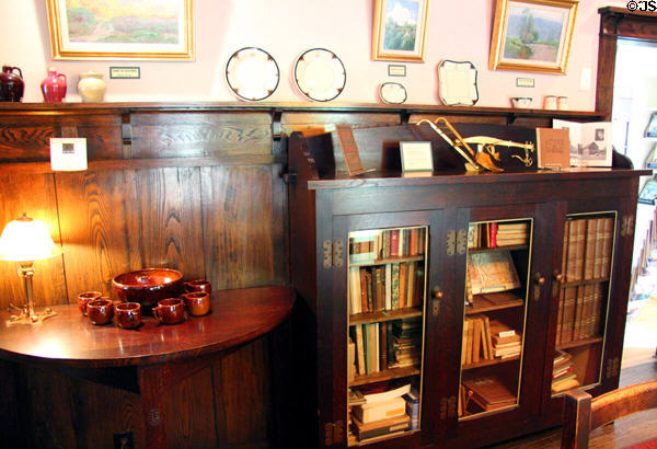 Side table & bookcase with ceramics in dining room at Elbert Hubbard Roycroft Museum. East Aurora, NY.
