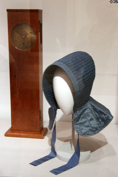 Shaker coffin wall clock (c1786) & sister's bonnet (19thC) from New Lebanon, NY at Metropolitan Museum of Art. New York, NY.