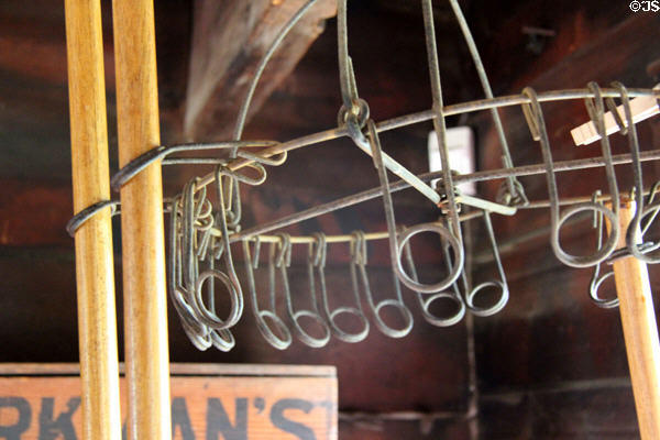 Broom rack where handles inserted through rings were held by friction in Luyster Store at Old Bethpage Village. Old Bethpage, NY.