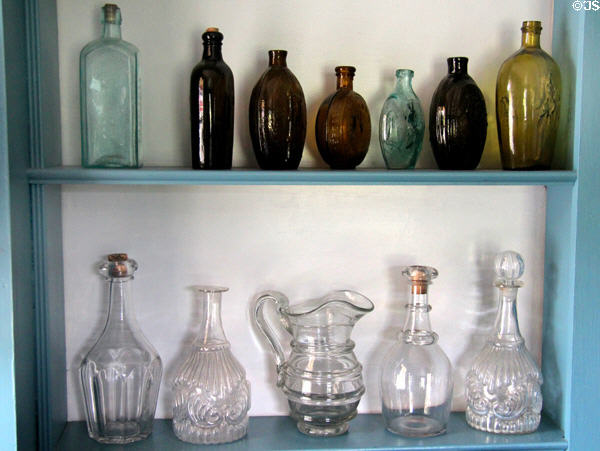 Early American glass bottles, pitcher & decanters in Noon Inn Barroom at Old Bethpage Village. Old Bethpage, NY.