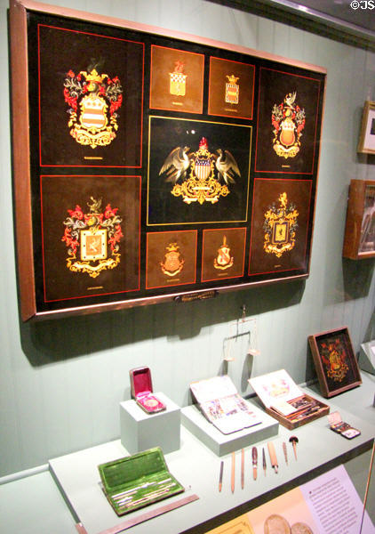 Display of heraldic panel paintings for coaches (1878) by Peter Barry of Brewster & Co. above his painting & drafting tools at carriage collection of Long Island Museum. Stony Brook, NY.