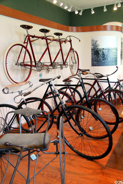 Collection of antique bicycles including Dayton Triplet (1898) on wall at Carillon Historical Park. Dayton, OH.