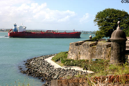 Tanker sails out of San Juan harbor past city walls linear park & walkway. San Juan, PR.