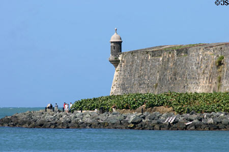Sentry box towers over people strolling along San Juan city walls. San Juan, PR.