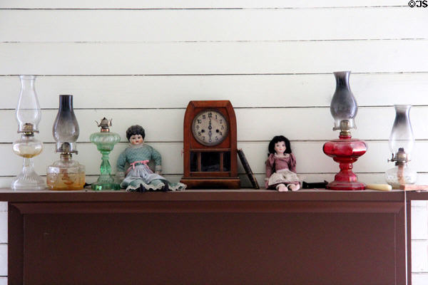 Oil lamps, mantle clock & dolls in Bell House at Pioneer Farms. Austin, TX.