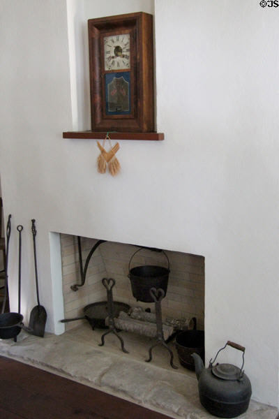 Shelf clock with crossed US flag design above fireplace in Baetge House at Conservation Plaza. New Braunfels, TX.