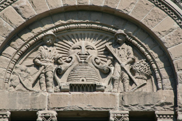 Utah seal in carved stone of miner & farmer flanking sun rising over beehive on Salt Lake City & County Building. Salt Lake City, UT.