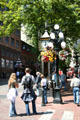 Visitors listen to whistles of Gastown Steam Clock. Vancouver, BC.