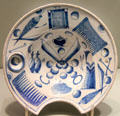 Barber basin decorated with barbering tools including face in small mirror on English delftware from London or Bristol at Gardiner Museum. Toronto, ON.