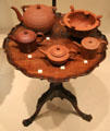 English red stoneware teapots & brazier atop small round Mahogany English table at Royal Ontario Museum. Toronto, ON.