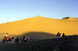 Traveling across Singing Sand Mountains of Dunhuang by camel. China.