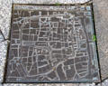 Modern bronze plaque in pavement with street map of Roman Köln within city walls near Roman Germanic Museum. Köln, Germany.