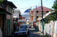 Cruise ship towers over end of narrow heritage old town street. Roseau, Dominica.