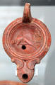 Roman oil lamp with dolphin symbol of sea god at Antikensammlungen. Munich, Germany.