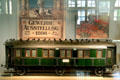 Model of Bavarian passenger wagon under poster of Berlin Trade Show at Nuremberg Transport Museum. Nuremberg, Germany.