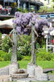 Modern sculpture of elongated male & female figures in front of wisteria. Lindau im Bodensee, Germany.