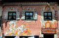 Building with decorative wooden sign for woodworker's shop & large mural on front facade. Oberammergau, Germany.