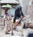 Woman with basket on head & man riding donkey in Giza. Egypt