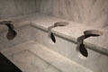 Replica of Roman latrine cleaned by running water at Pont du Gard museum. Nimes, France.