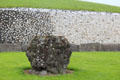 Newgrange standing stone against black & white wall of passage tomb. Ireland.
