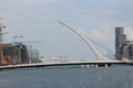 Samuel Beckett Bridge shaped like Irish harp over River Liffey with cruise ship in distance. Dublin, Ireland.