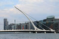 Samuel Beckett Bridge over River Liffey evokes shape of Irish harp & can rotate 90 degrees to allow river traffic. Dublin, Ireland.