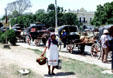 Women carries load past horse carts at Izamal market. Mexico.