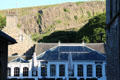 Holyrood Palace cafe building with glass roof against Salisbury Crags volcanic rock formation of Arthur's Seat. Edinburgh, Scotland.
