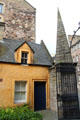 Yellow heritage house behind gate with pyramidal post near Canongate on Royal Mile. Edinburgh, Scotland.