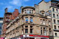 Grecian-style sandstone commercial building with chamfered corner bays. Glasgow, Scotland.