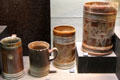 Earthenware tankards with turned decoration iron-stained brown plus additional impressed designs like royal seals made in North Straffordshire at Potteries Museum & Art Gallery. Hanley, Stoke-on-Trent, England.