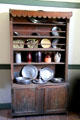 Cabinet with ceramics & pewter in brick house at Ulster American Folk Park. Omagh, Northern Ireland.