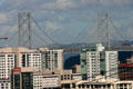 Oakland Bay Bridge spans above Frisco highrises. San Francisco, CA.