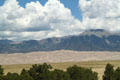 Layers of clouds, mountains, dunes & trees at Great Sand Dunes National Park. CO.
