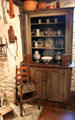 Cupboard with pewter, ceramics behind high chair at Henry Whitfield State Museum. Guilford, CT.