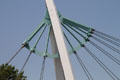 Pedestrian suspension bridge structure over Arkansas Rivers beyond Keeper of the Plains sculpture. Wichita, KS.