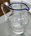 Blown & engraved clear glass pitcher with blue rim at Sandwich Glass Museum. Sandwich, MA.