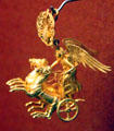 Ancient Greek gold earring of Nike driving her chariot from Peleponnesos at Museum of Fine Arts. Boston, MA.
