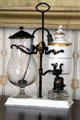 Coffeemaker on stand prob. French wherein white porcelain chambers with gold bands contains water & coffee over oil lamp heat forcing coffee through tube into glass carafe at Lindenwald. Kinderhook, NY.