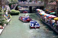 Boats cruise San Antonio River beside Riverwalk. San Antonio, TX.