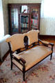 Wood & upholstered settee before glass-front bookcase at Chambers House Museum. Beaumont, TX.