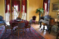 Parlor music room with table, piano & harp at East Terrace House. Waco, TX