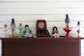 Oil lamps, mantle clock & dolls in Bell House at Pioneer Farms. Austin, TX.