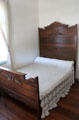 Finely carved wooden bed & crochet coverlet in Jahn House at Conservation Plaza. New Braunfels, TX.
